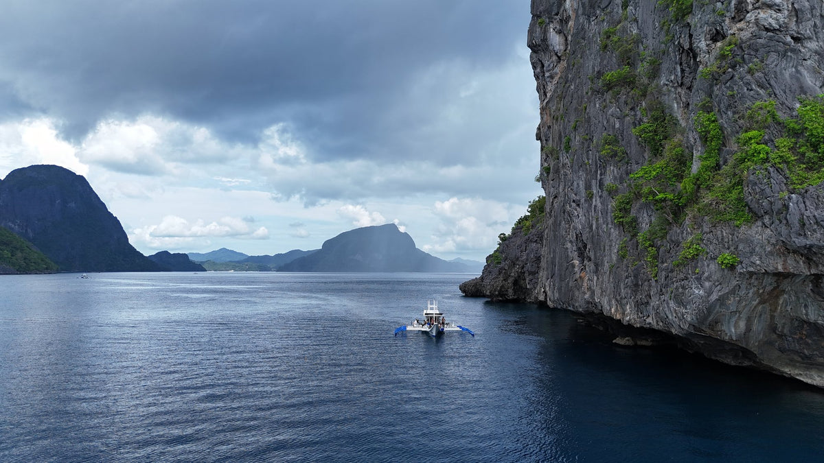Dive boat beneath the limestone cliffs of Bacuit Bay, El Nido