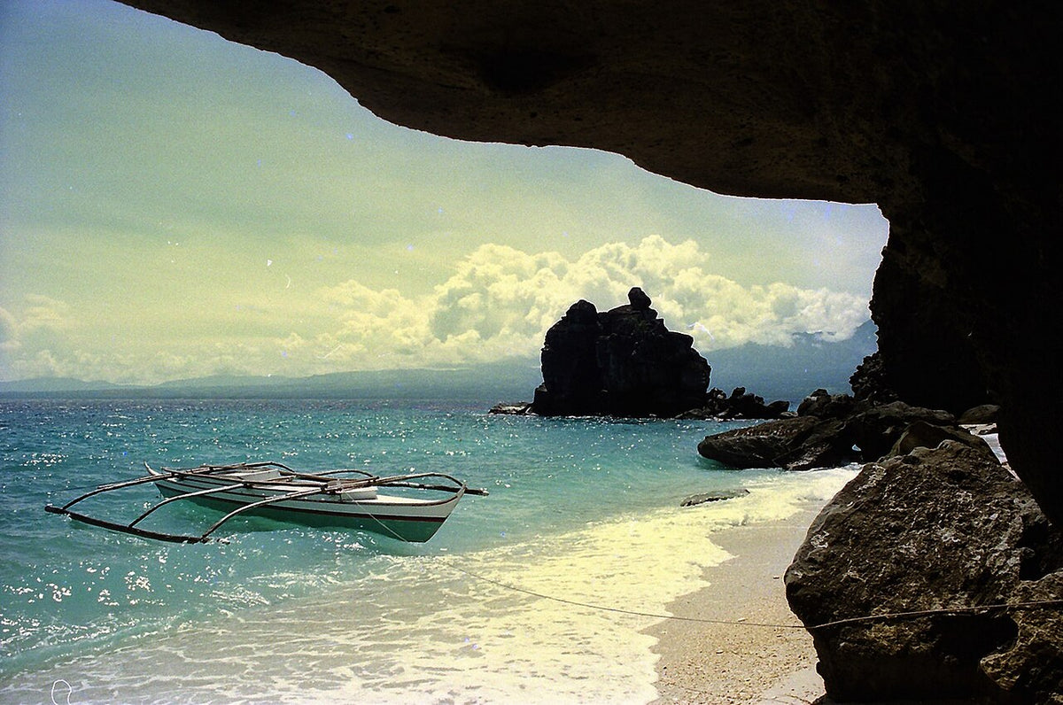 Outrigger boat and a rocky cove on Apo Island, Negros