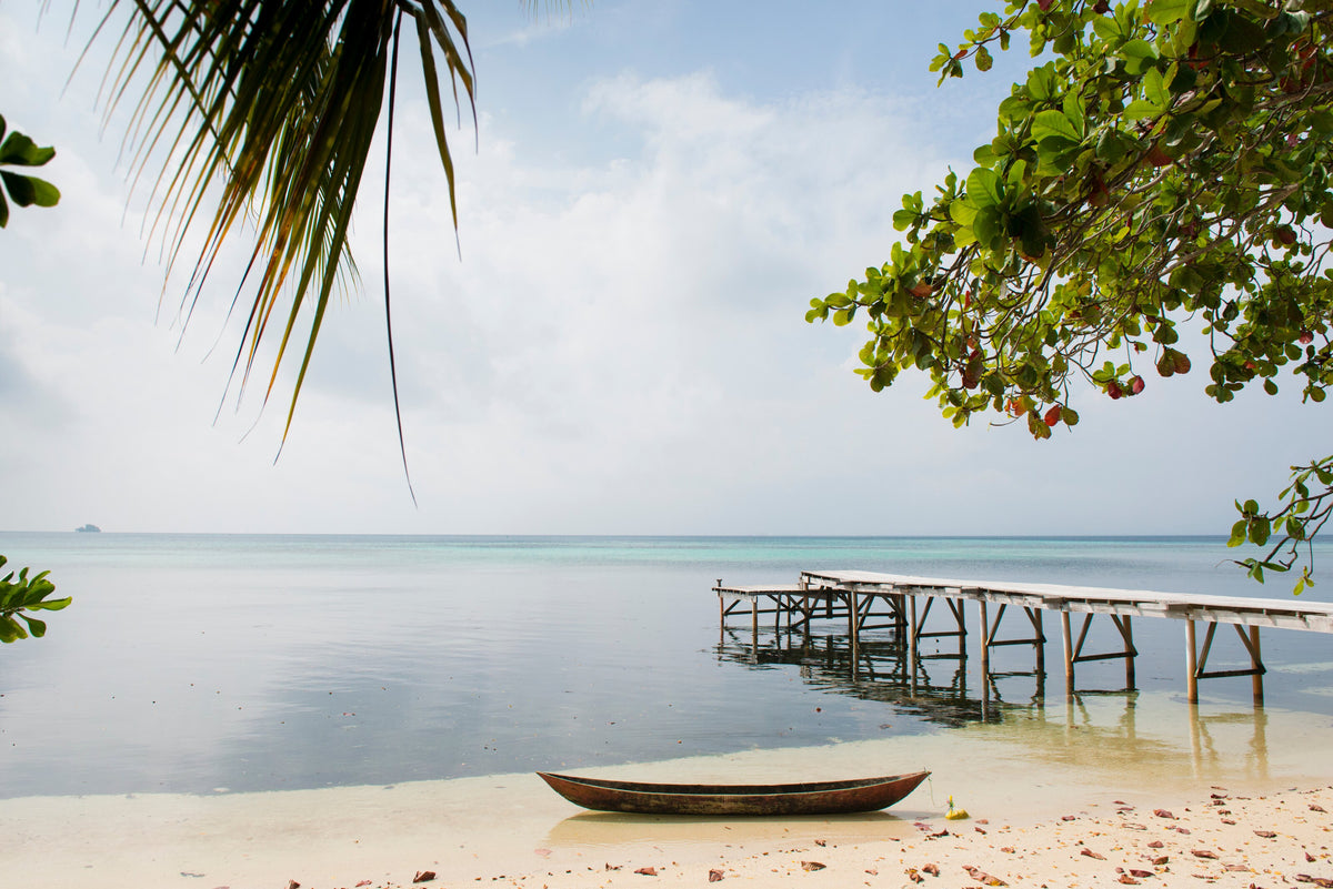 Small wooden boat and jetty beside a palm-fringed beach in Gizo, Solomon Islands