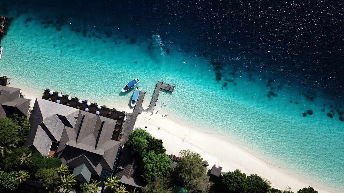 Aerial view of white sand, coastal buildings and clear water on Mataking Island, Malaysia