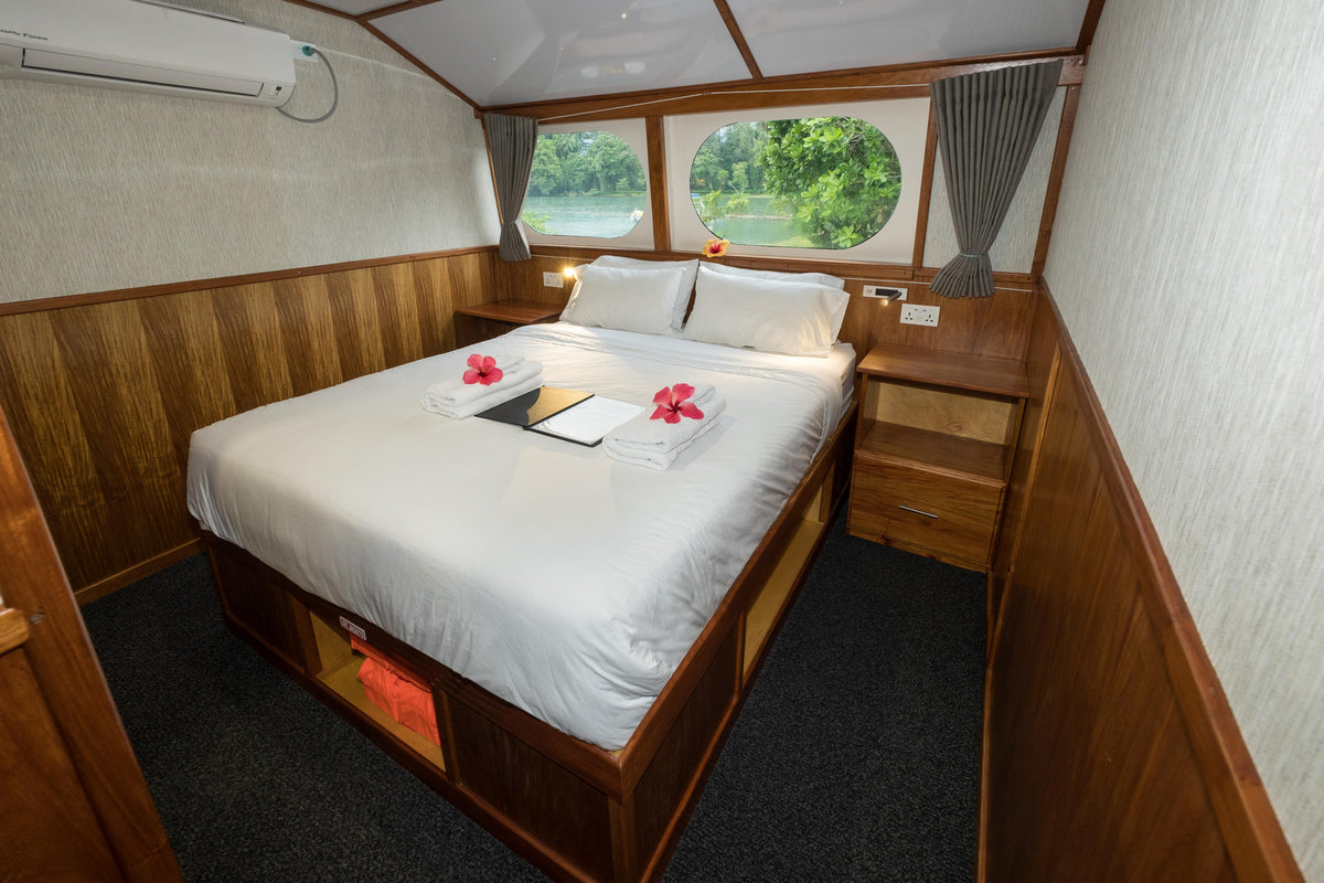 Queen bed and sea-view windows in a cabin aboard MV Oceania. Photo: Peter Lange.