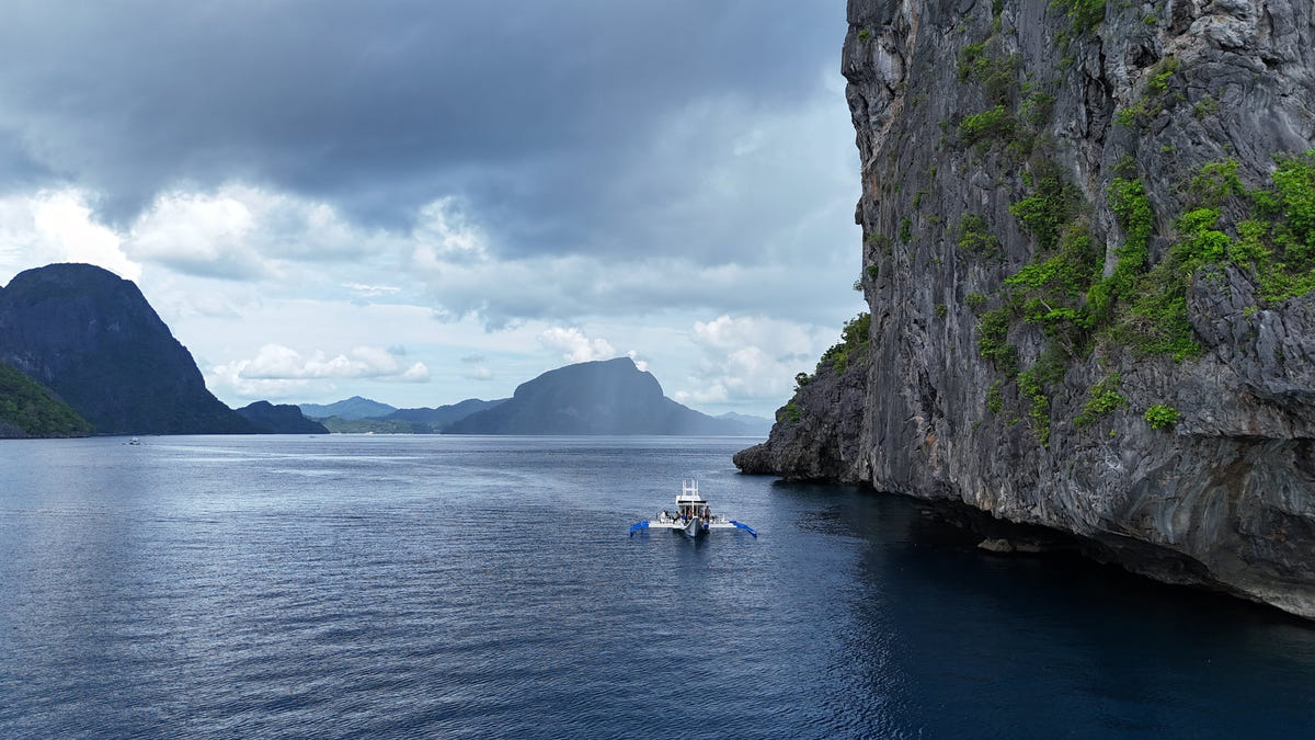 Dive boat beneath the limestone cliffs of Bacuit Bay, El Nido