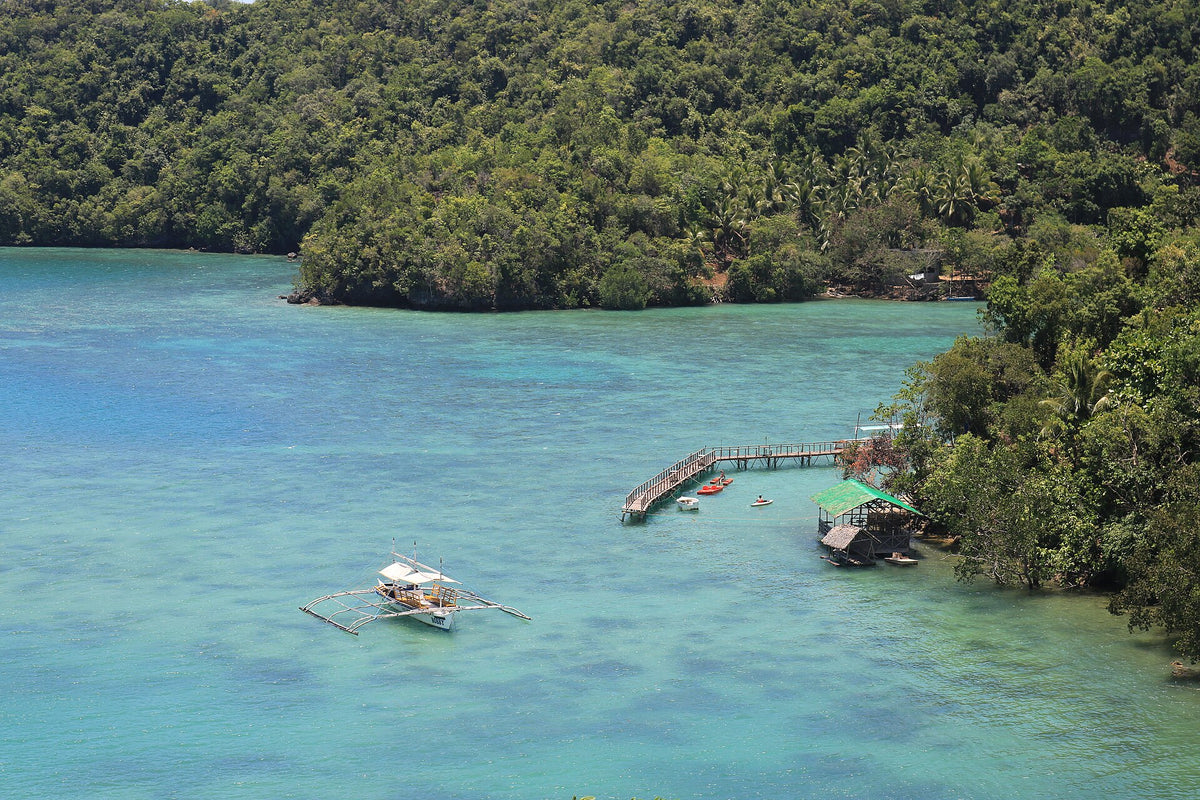 Outrigger boat in a turquoise bay along the Sipalay coast, Negros