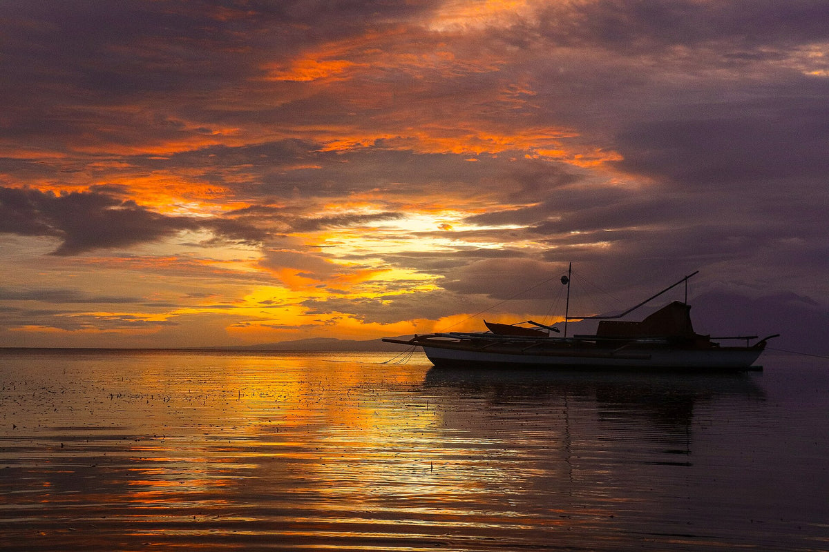 Boat silhouetted against sunset at San Juan, Siquijor